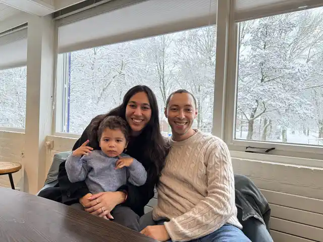 A family sitting together indoors beside a snowy winter view.